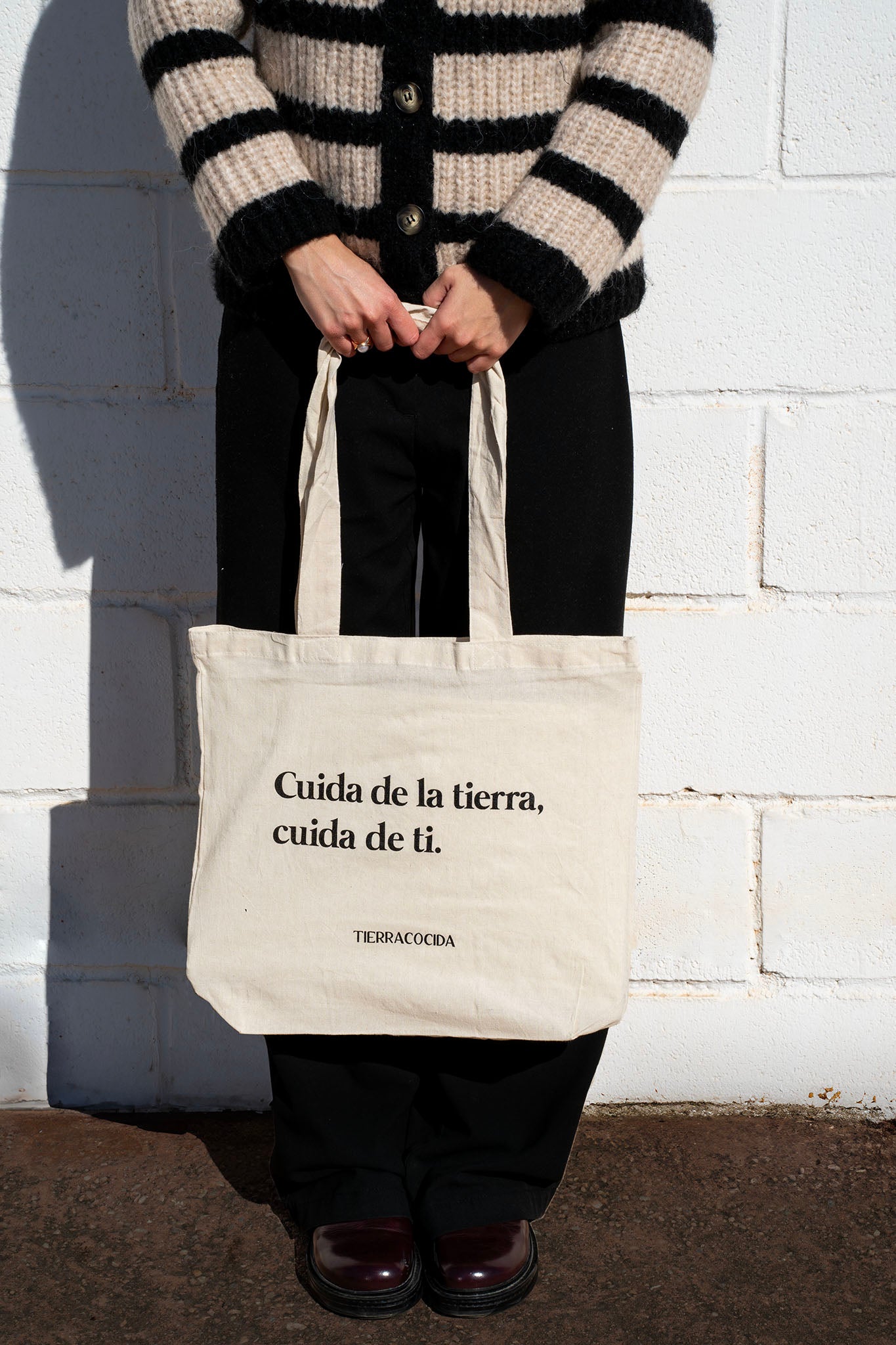 Chica sosteniendo una bolsa de tela con frase "Cuida de la tierra, cuida de ti"